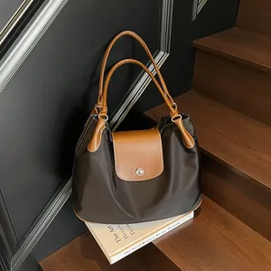 Large capacity black nylon tote bag with brown leather handles on wooden stairs