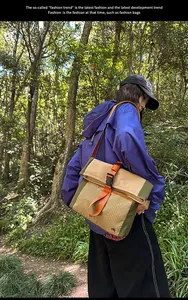 Detail of khaki and olive canvas messenger bag with vibrant orange strap and buckle