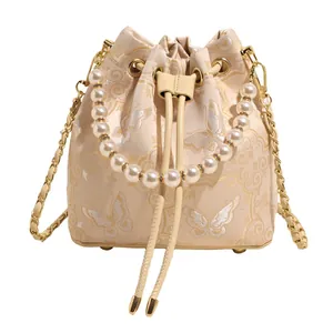 Elegant bucket bag with pearl handle, butterfly embroidery and gold chain strap