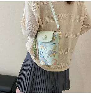 Detail of mint green crossbody phone bag with elephant pattern and star charm on model