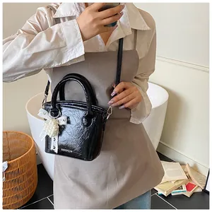 Detail der schwarzen Lackleder-Eimertasche mit Spitzenschleife und Perlenherz-Anhänger