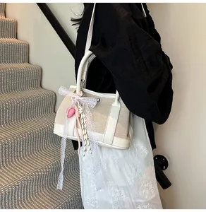 Detail of canvas bucket bag with leather trim and decorative lace bow on stairs