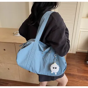 Light blue nylon tote bag with plush sheep charm shown on shoulder in daily setting