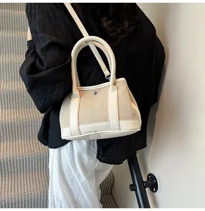 Chic beige color-block crossbody bag in lychee leather and canvas on a casual shoulder