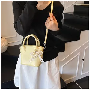 Detail der hellgelben Beuteltasche mit Perlenanhänger und Spitzenschleife am Modell