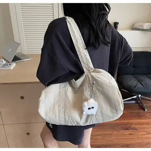 Detail of beige nylon tote bag featuring a white plush charm and minimalist shoulder strap