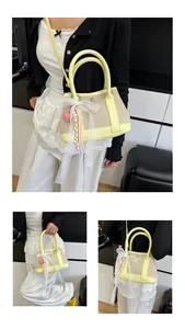 Detail of beige canvas and yellow leather handbag with lace bow and heart charm