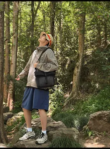 Outdoor lifestyle shot of a large black messenger bag styled with gorpcore hiking apparel