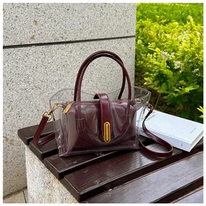 Detail view of transparent PVC tote bag with burgundy leather inner pouch and gold hardware