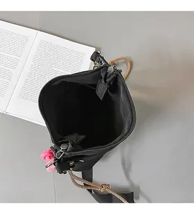 Dettaglio borsa a tracolla in nylon nero con cinturino leopardato e ciondolo rosa