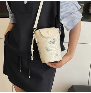 Detail of cream mini crossbody bag with green leaf pattern and star ornament
