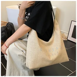 Dettaglio della borsa hobo a righe intrecciata con trama di paglia e ricamo di lettere