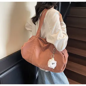Close-up of pink nylon tote bag with wide shoulder straps and cute plush pendant charm