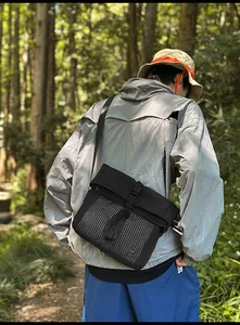Detail of black tactical messenger bag with mesh pocket and buckle on a hiking trail