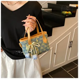 Dettaglio borsa a cestino in denim con stampa corona, perle e fiocco di nastro verde