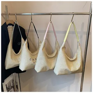 Dettaglio di borse hobo in paglia intrecciata con spalline colorate su una gruccia