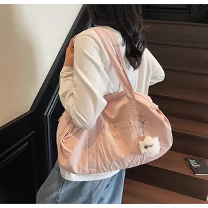 Pink nylon shoulder bag featuring a white plush bear charm on minimalist stairs