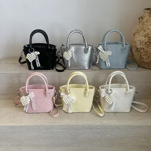Mini-Eimertaschen in Faltenoptik in mehreren Farben mit Herz-Perlen-Anhängern auf Steinstufen