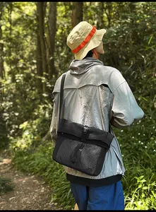 Outdoor lifestyle view of durable nylon messenger bag with white mesh pocket and buckle
