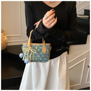 Dettaglio della mini borsa in denim con ricamo, fiocco di perle e manici in ecopelle