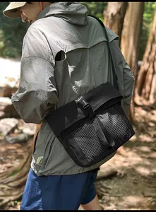 Outdoor crossbody messenger bag with white grid pattern shown in a forest setting