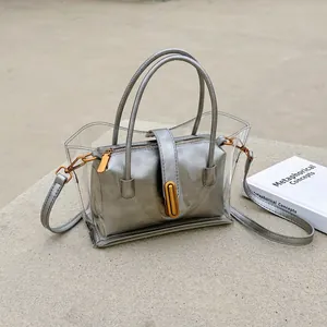 Stylish clear PVC tote bag with silver inner pouch and shoulder strap on stone surface