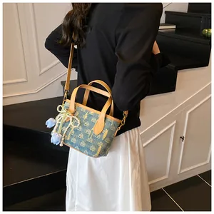 Dettaglio della mini borsa tote in denim con ciondolo a fiore e tracolla di perle