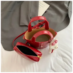 Dettaglio set borsa a secchiello in pelle verniciata rossa con pochette e orsetto