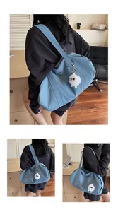 Detail of blue nylon tote bag with wide strap and cute white plush sheep charm