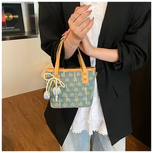 Dettaglio borsa a secchiello in denim con ciondolo di perle e finiture in pelle kaki