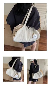 Close-up of beige nylon tote bag featuring a side pocket and cute plush monster pendant