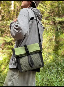 Outdoor view of a green and black messenger bag featuring reinforced mesh texture