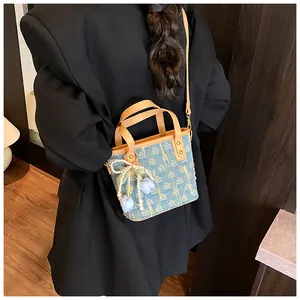Dettaglio borsa in denim con motivi geometrici gialli e ciondolo a fiore di perle