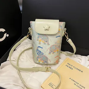 Pale green cylindrical crossbody phone bag with ethnic elephant pattern and star detail