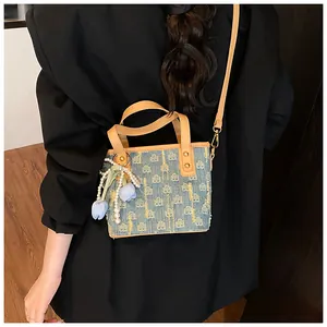 Borsa a secchiello in denim con manici in pelle e ciondolo a tulipano su blazer nero
