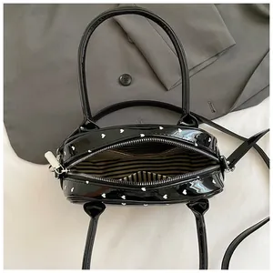 Borsa in pelle verniciata nera con motivi a cuore bianchi e tracolla regolabile