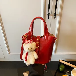 Borsa a secchiello rossa lucida con ciondolo a orsetto e tracolla staccabile