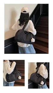 Close-up of black nylon tote bag featuring front snap pocket and white plush monster charm