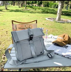 Detail of light blue waterproof canvas messenger bag with flap cover on outdoor grass
