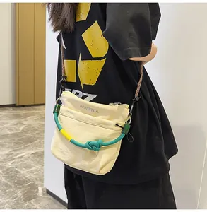 Dettaglio della borsa a tracolla in nylon beige con manico in corda intrecciata colorata