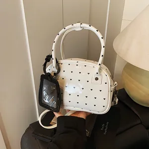 Borsa a mano bianca con stampa a cuori e tracolla in un ambiente minimalista