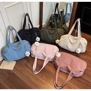 Detail of multi-colored waterproof nylon tote bags with plush sheep charms on wood floor