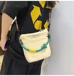 Dettaglio di una borsa a tracolla in nylon crema con tracolla in corda verde su un modello