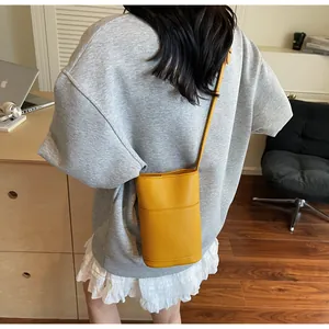 Borsa a secchiello gialla con trama litchi indossata da una modella vista da dietro