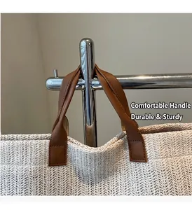 Dettaglio dei manici in pelle marrone e della trama in paglia beige della borsa tote
