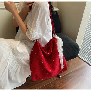 Dettaglio di una borsa tote in tela rossa a fiori con decorazione a fiocco in pizzo