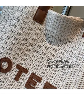 Dettaglio macro della borsa tote in paglia beige con trama ondulata e scritte in pelle marrone
