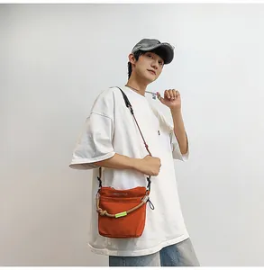 Borsa a tracolla in nylon arancione in stile outdoor indossata da un modello con t-shirt