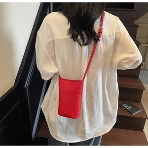 Dettaglio borsa a tracolla in pelle martellata rossa indossata con camicia di lino