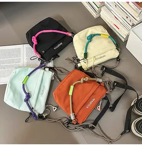 Dettaglio di borse a tracolla in nylon con manici in corda annodata e stampa di lettere